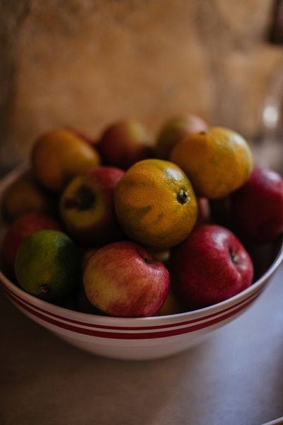 En skål med äpplen och citrusfrukter på ett bord.